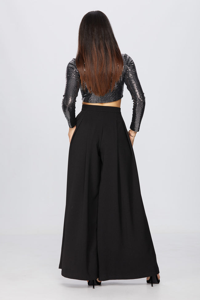 back view of a woman posing in a studio wearing a black pair of diy sewn pants pattern