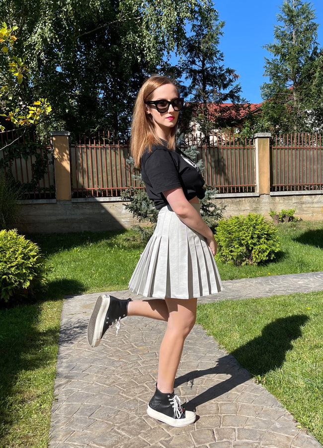woman posing in a skirt and black shirt outfit
